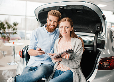 Couple sitting in the back of a car trunk reviewing auto insurance in Lincolnton, GA